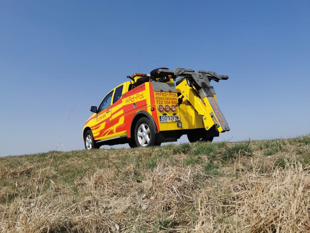 Laweta Środa Śląska podczas transportu auta osobowego na poboczu drogi